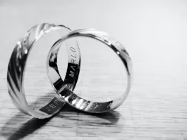 Alianzas de plata grabadas sobre superficie de madera, símbolo de boda de plata