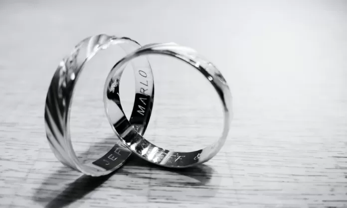 Alianzas de plata grabadas sobre superficie de madera, símbolo de boda de plata