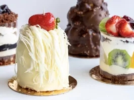 Cuatro postres individuales con chocolate, hebras de chocolate blanco y frutas frescas sobre fondo claro