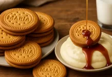 El legado de la galleta María: el sabor de un clásico que sigue vigente Taza de café latte con arte de leche acompañada de galletas María sobre mantel iluminado por la mañana.