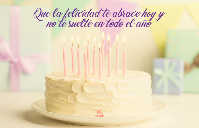 Pastel de cumpleaños con velas encendidas y frase: Que la felicidad te abrace hoy y no te suelte en todo el año — fondo suave y colores pastel.