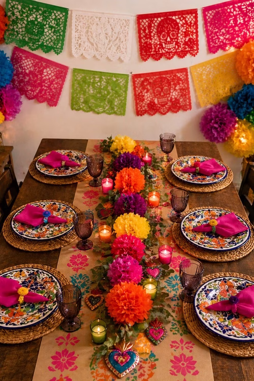 Mesa inspirada en fiesta mexicana con papel picado, flores de papel y vajilla colorida