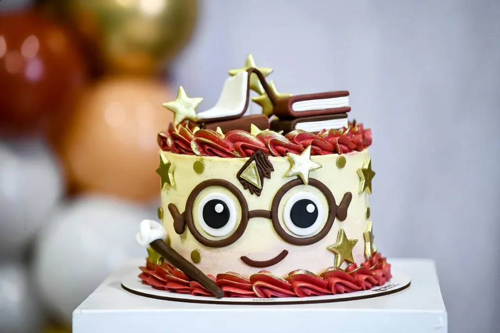 Tarta Harry Potter infantil con gafas, varita, libros, estrellas doradas y decoración roja en crema.