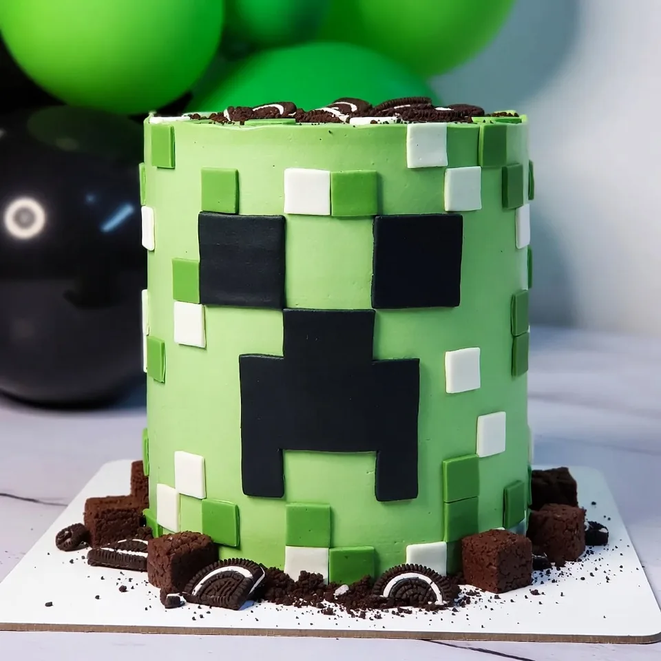 Pastel redondo verde con cara Creeper, cuadros de fondant y decoración de galletas con brownie