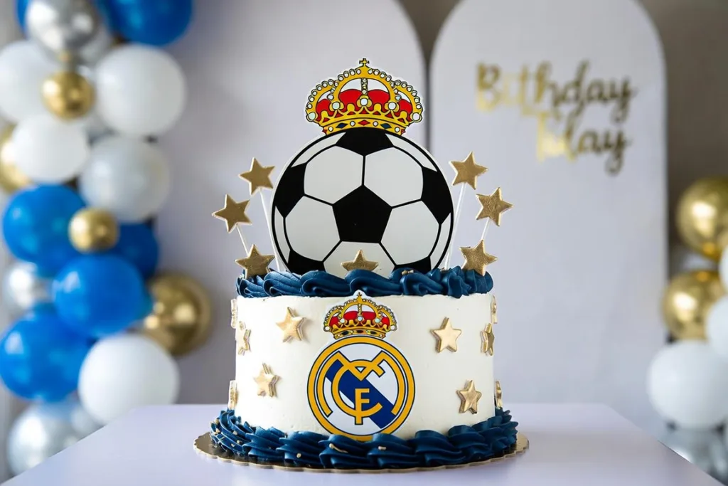 pastel blanco con balón, corona y estrellas doradas en mesa de cumpleaños