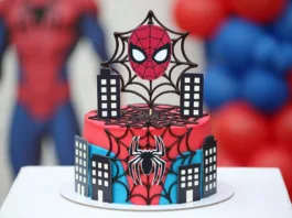 Tarta Spiderman roja y azul con telarañas, edificios decorativos y topper de máscara para cumpleaños infantil