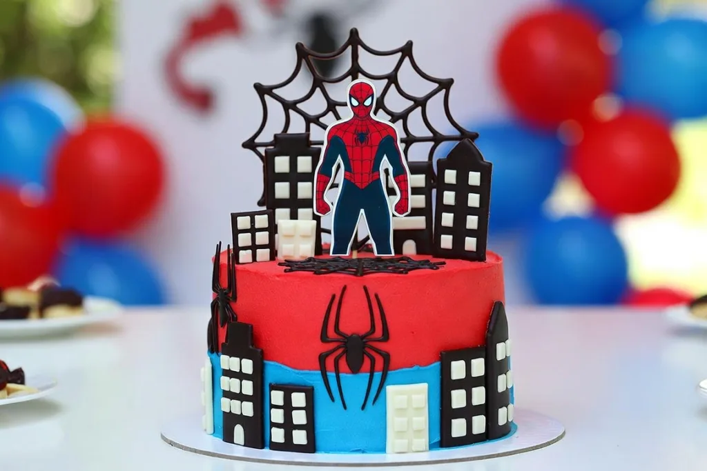 Pastel rojo y azul con edificios decorativos, telaraña superior y globos de fiesta al fondo